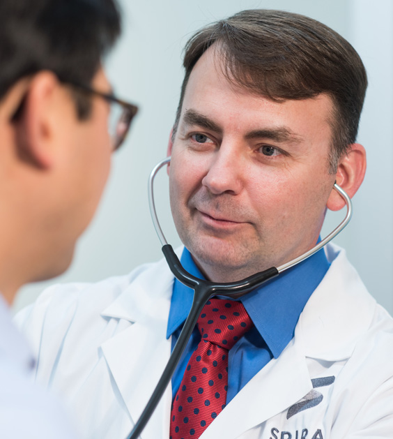 A Spira Care doctor using a stethoscope on a patient.