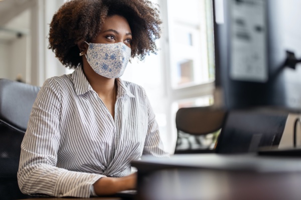 Woman working on a computer with a mask